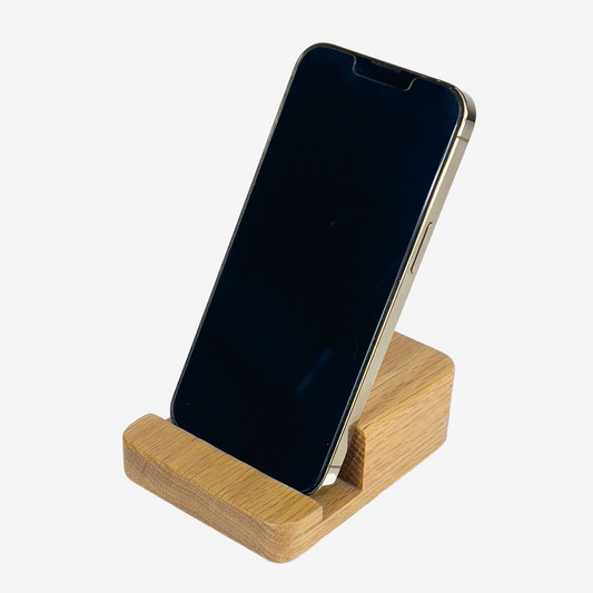 Lux Navia oak wooden phone stand holding a smartphone, with the image taken from the front, combining a minimalist aesthetic with practical functionality for any workspace or home.