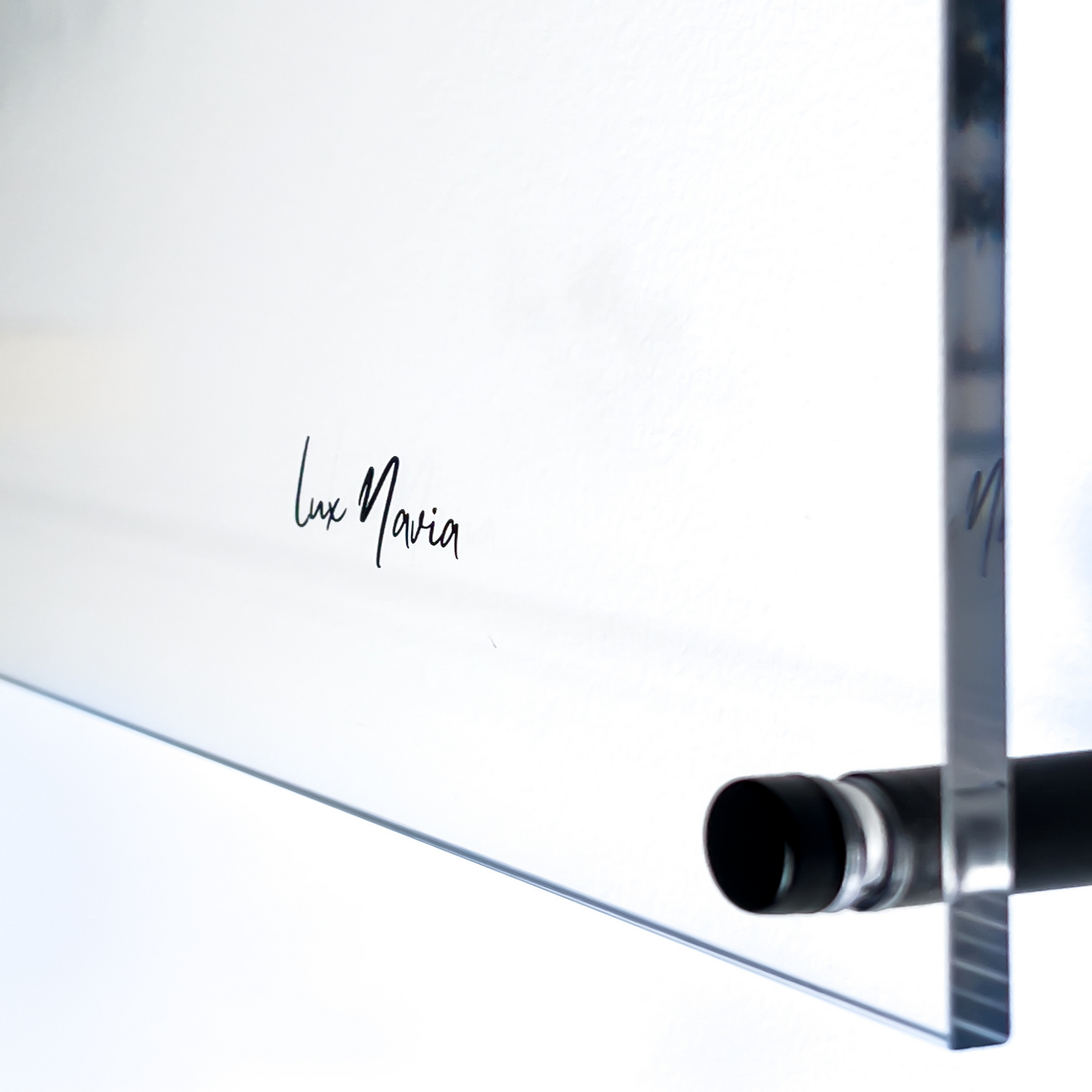 Close-up view of the Lux Navia logo etched on a clear acrylic surface, showcasing a sleek and modern design element with a minimalistic aesthetic.