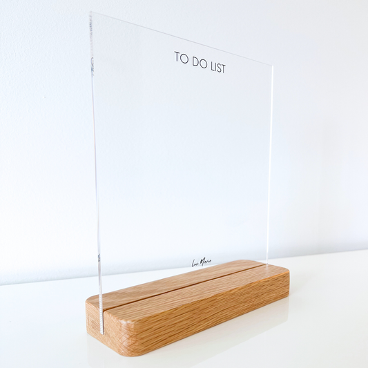 Front view of a clear acrylic to-do list with a sturdy oak stand, designed for daily task organization in a minimalist home office. Compatible with dry and wet erase markers for easy reuse.